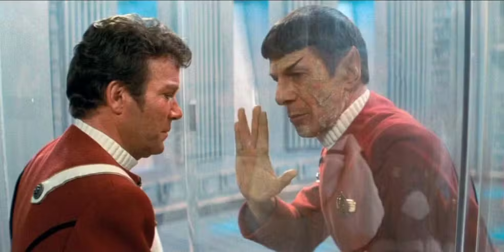 Capitão Kirk e Spock se despedem através de um vidro, com Spock fazendo a famosa saudação vulcana.