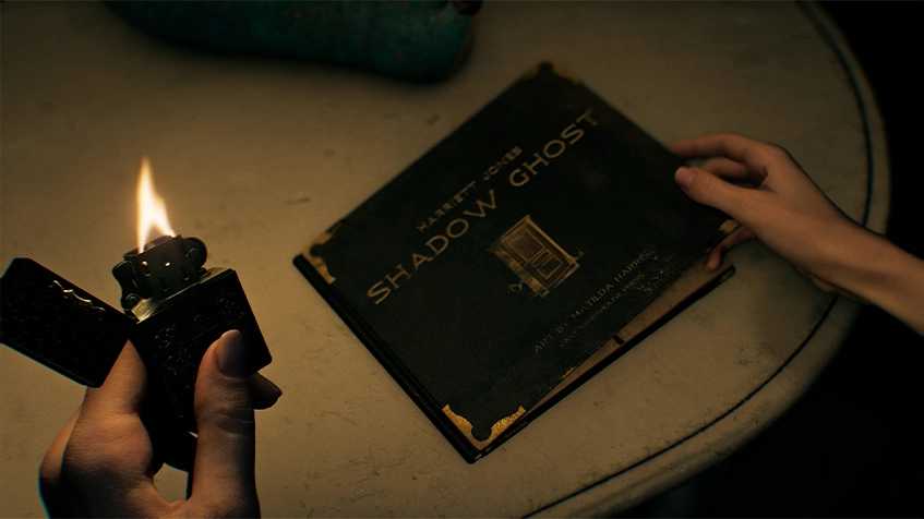 Visão em primeira pessoa das mãos de Grace Ashcroft em um ambiente mal iluminado. A mão esquerda segura um isqueiro aceso, enquanto a direita abre um livro preto intitulado "Shadow Ghost", de Harriett Jones. O livro está sobre uma mesa circular e a chama do isqueiro é a principal fonte de luz da cena.