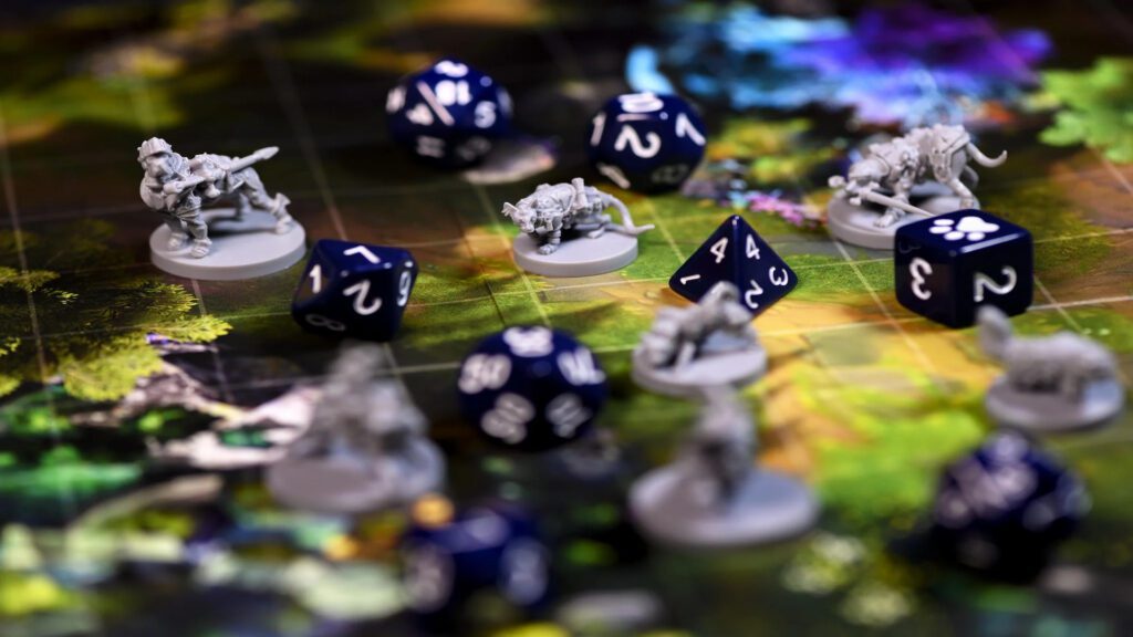 A imagem mostra em close um jogo de RPG acontecendo, com dados e miniaturas.